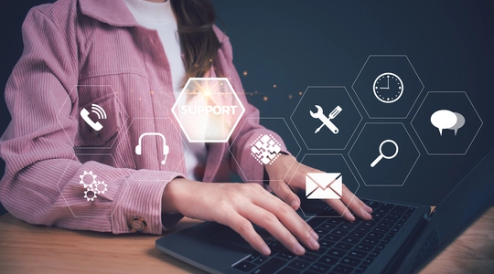 Person typing at a laptop with various tech support icons